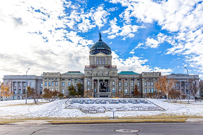 Executive Director’s Message: Building on Momentum; Large stone building with a central dome under a bright blue sky, surrounded by a snowy lawn and autumn trees, conveying a peaceful, stately atmosphere.